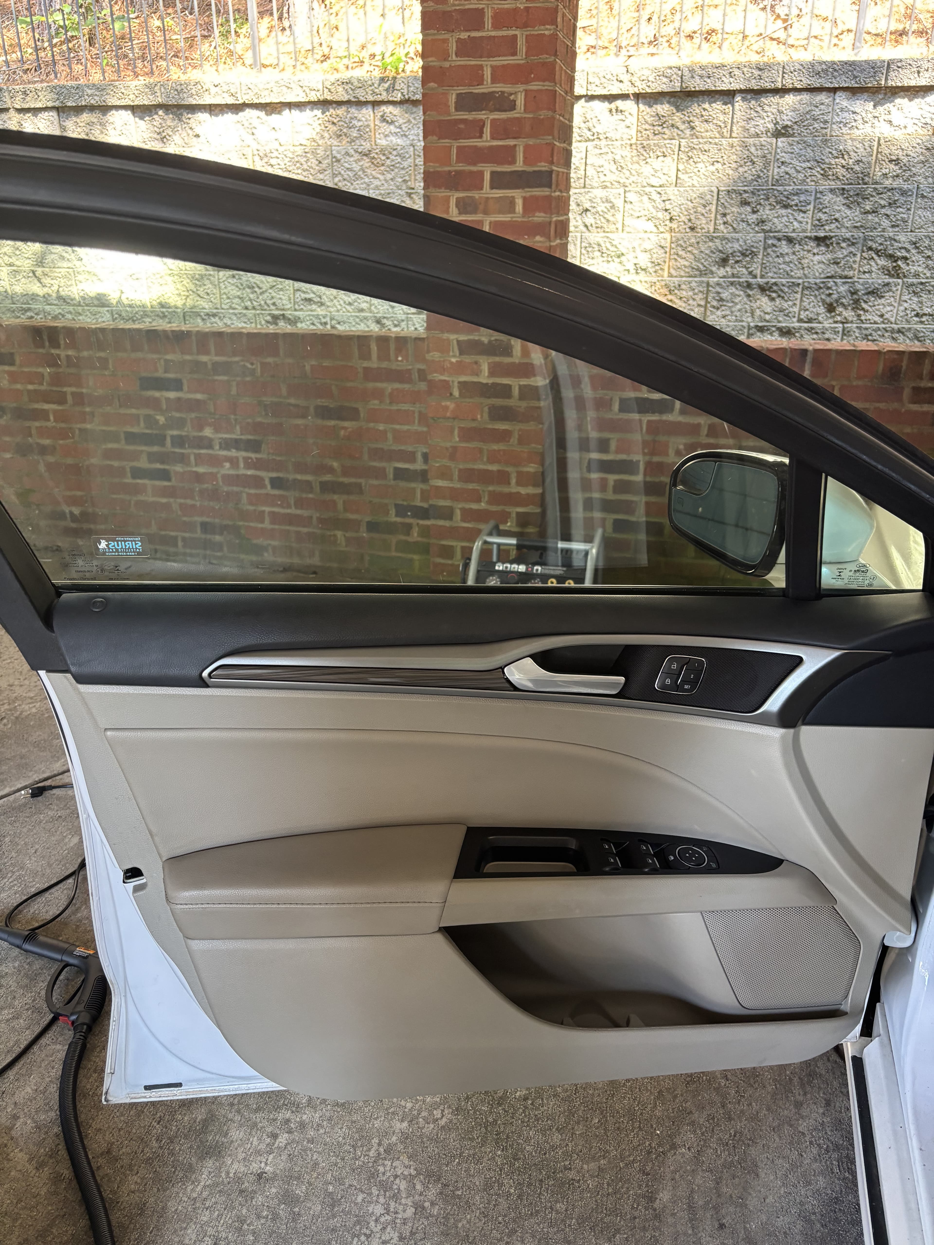 Open car door featuring a two-tone tan and black interior panel with silver trim.